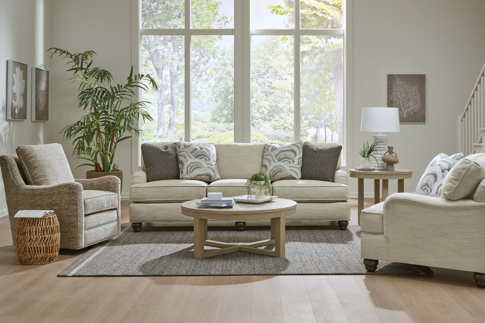 Living room with beige sofa, armchairs, and coffee table in a well-lit room.

